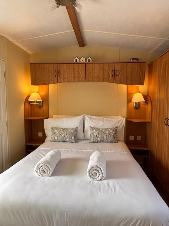 a bedroom with a large white bed with towels on it at Seaside Escape 2-Bed Caravan at Seven Bays Park in St Merryn