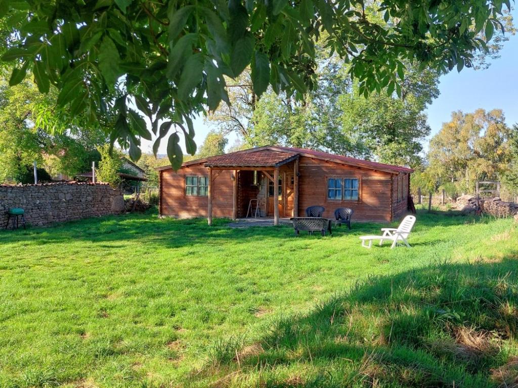 a log cabin with a chair in a yard at Pause nature au cœur des forêts in Saint-Pal-de-Senouire