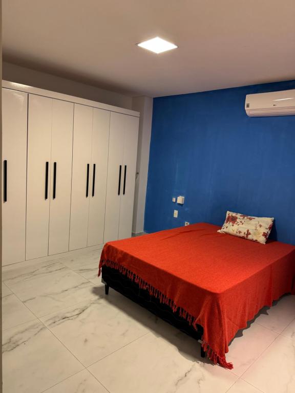 ein Schlafzimmer mit einer blauen Wand und einem Bett mit einer roten Decke in der Unterkunft Sanzecasadapraia in São José da Coroa Grande