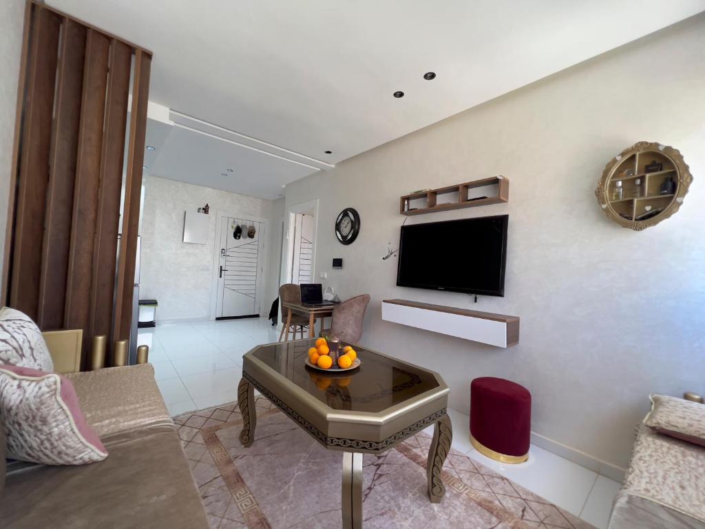 a living room with a table and a tv on a wall at Le Style 