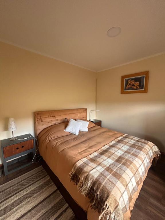 Un dormitorio con una cama y una mesa con una lámpara. en Confortable cabaña de campo, en Coyhaique