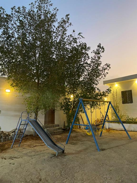 a couple of swings in front of a tree at إستراحة البستان in Ash Shuwaybiţ