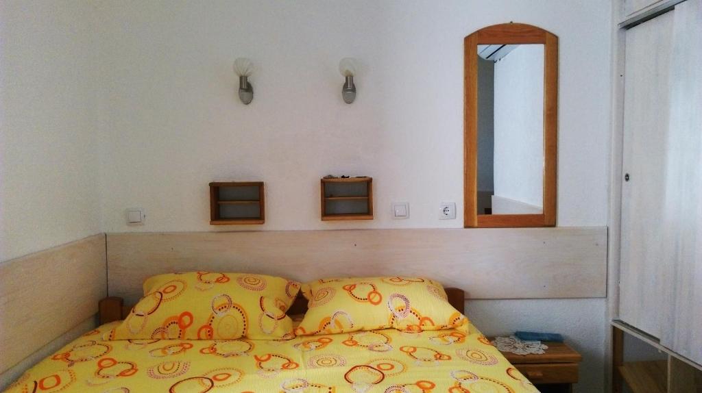 a bed with a yellow comforter and a mirror at Ema Apartments in Ulcinj