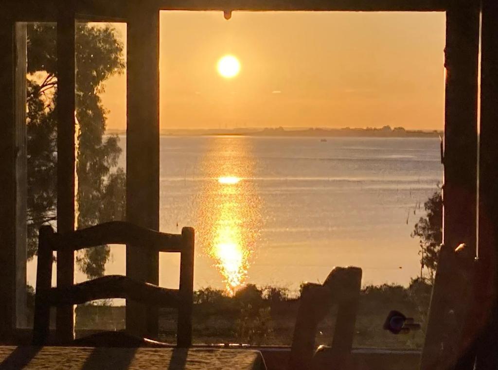 una ventana con silla y vistas a la puesta de sol. en Site exceptionnel accès mer grands espaces, en Ile-aux-Moines