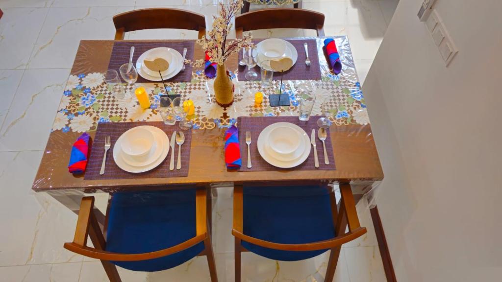 een houten tafel met stoelen en borden erop bij Samara Villa by Trillium Residencies in Nugegoda