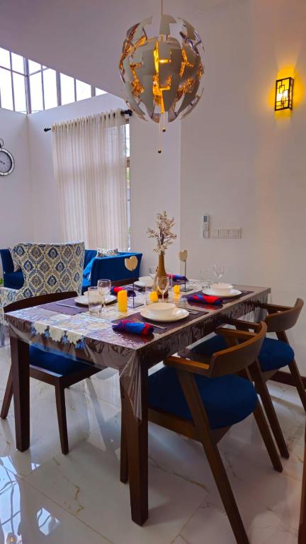 a dining room table with blue chairs and a chandelier at Samara Villa by Trillium Residencies in Nugegoda