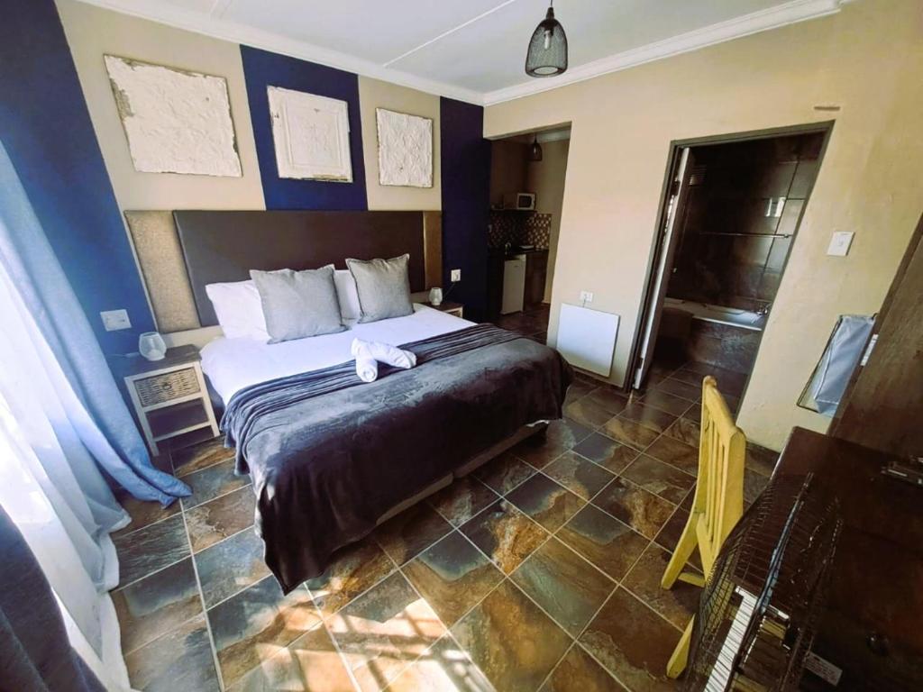 Un dormitorio con una cama grande con paredes azules. en Edenville Guesthouse, en Lichtenburg