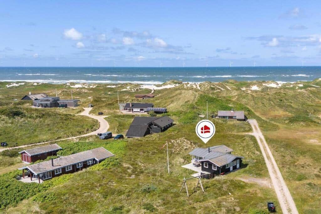 een groep huizen op een heuvel bij de oceaan bij 1197-Ringkobing-Nordlysvej-17 in Søndervig