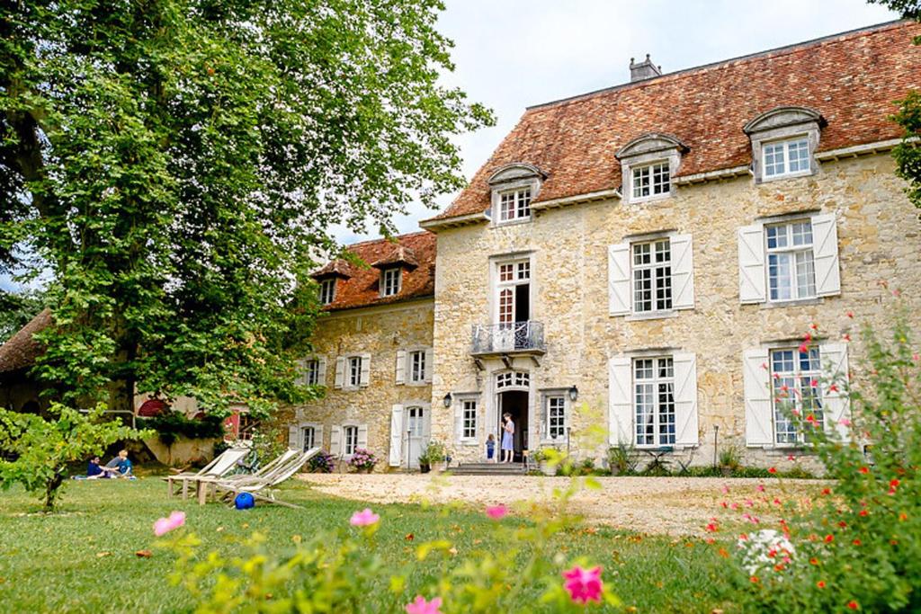 uma antiga casa de pedra com um jardim em frente em Château d’Orion em Orion