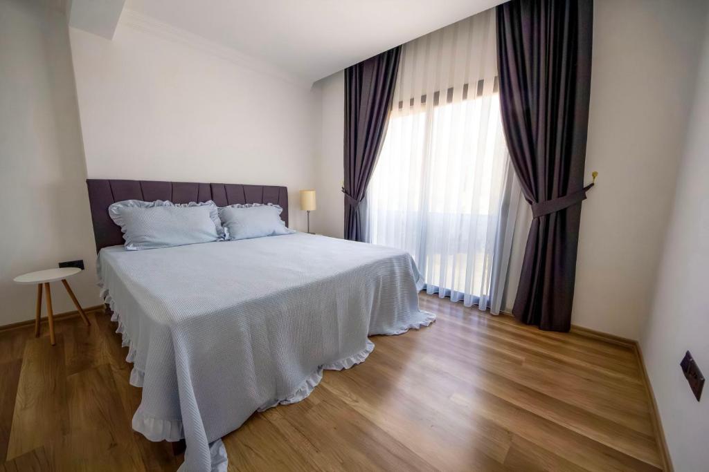 Cette chambre comprend un lit avec des draps blancs et une grande fenêtre. dans l'établissement Apartment Northern Cyprus, 