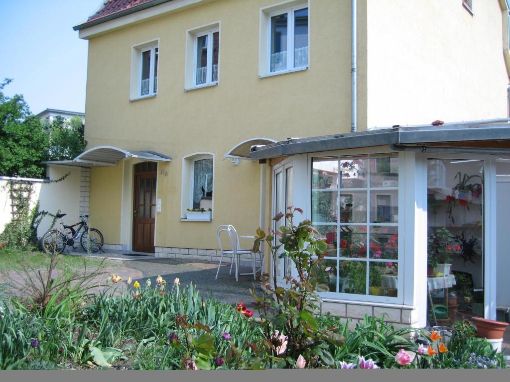 ein gelbes Haus mit Wintergarten davor in der Unterkunft Pension Alter Zausel in Weimar