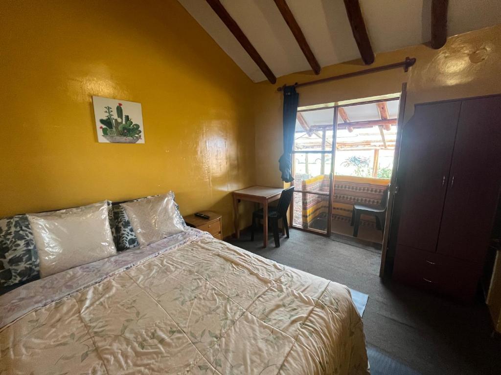 皮萨克Intihuatana Hostel的一间卧室，配有一张床、一张书桌和一扇窗户