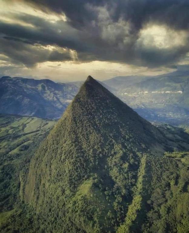 a large hill with trees and mountains in the background at Finca Crucytania in Titiribí