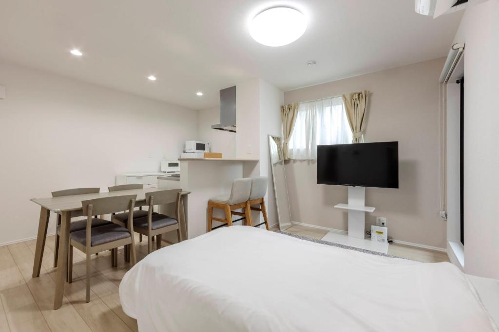 a bedroom with a bed and a table and a tv at Anecis Honjin in Nagoya