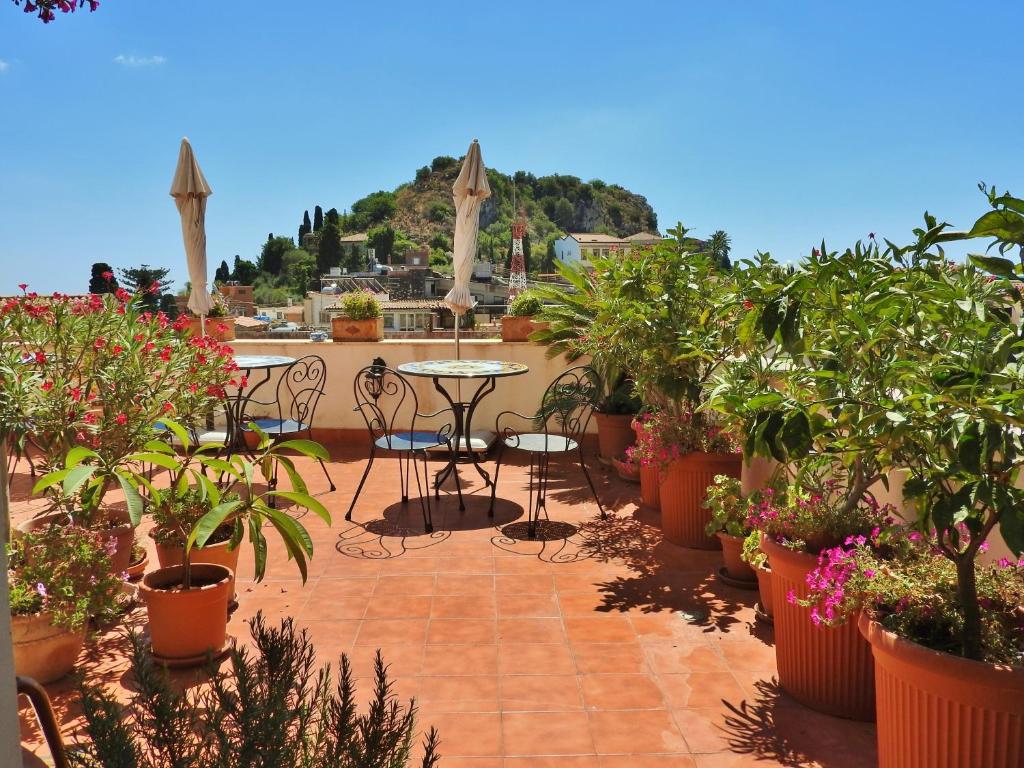 a patio with a table and chairs and potted plants at Cielo di Taormina in Taormina