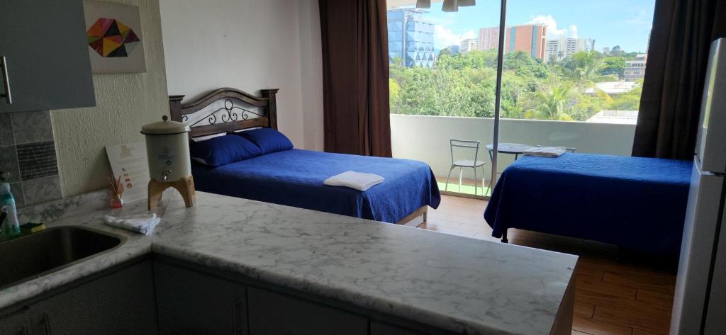 a kitchen with two beds and a sink in a room at Apartamento Reforma Ciudad de Guatemala in Guatemala