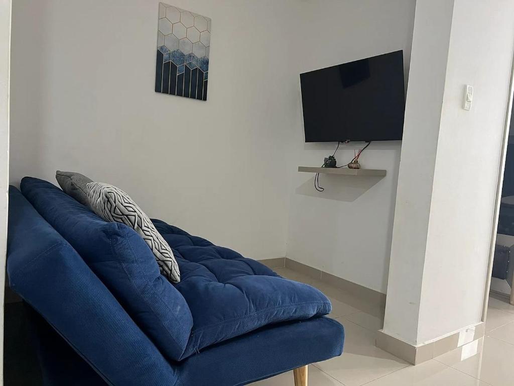 ein blaues Sofa im Wohnzimmer mit einem TV in der Unterkunft Apto cerca del Río Guatapurí Valledupar in La Elvira