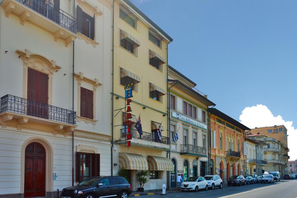 a yellow building with cars parked on a city street at Hotel Pardini in Viareggio