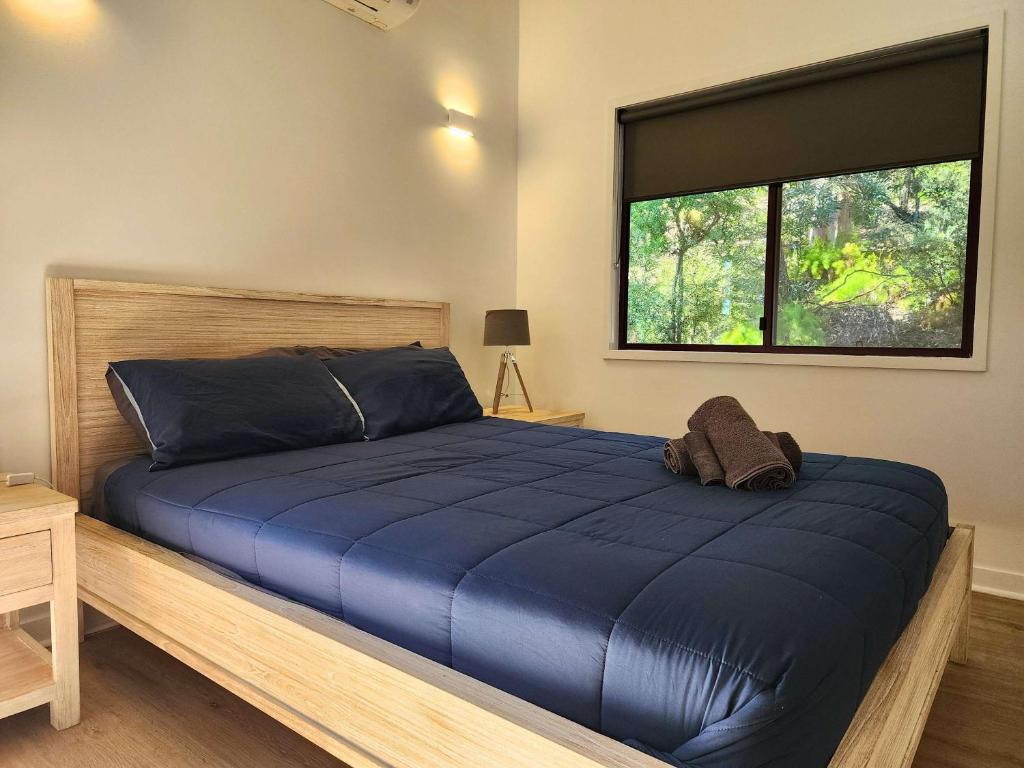 フレーザー島にある718 Cooloola Villa at Kingfisher Bay, K'gari Fraser Islandのベッドルーム(大型ブルーベッド1台、窓付)