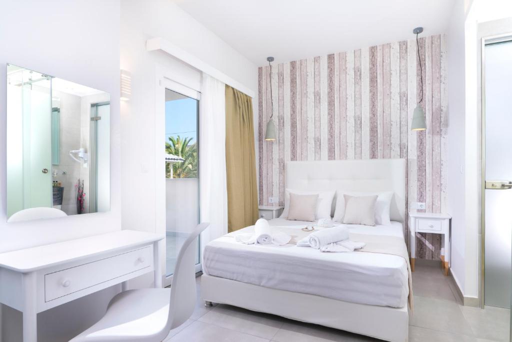 a white bedroom with a white bed and a mirror at Estian Deluxe in Limenaria