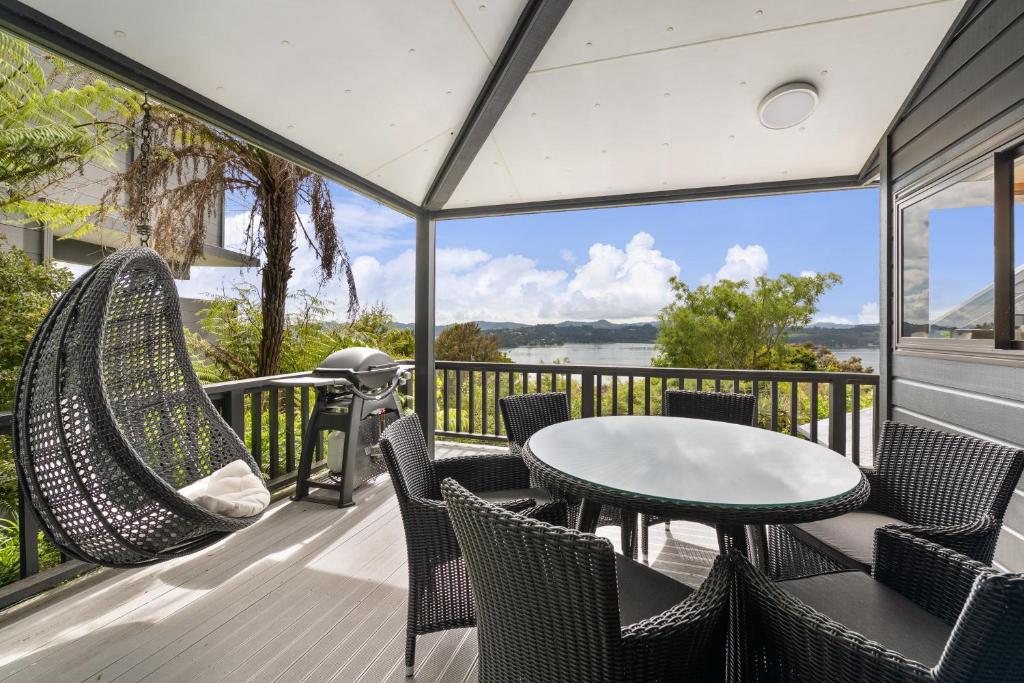 a patio with chairs and a table and a swing at Sullivans Retreat - Paihia Holiday Home in Paihia