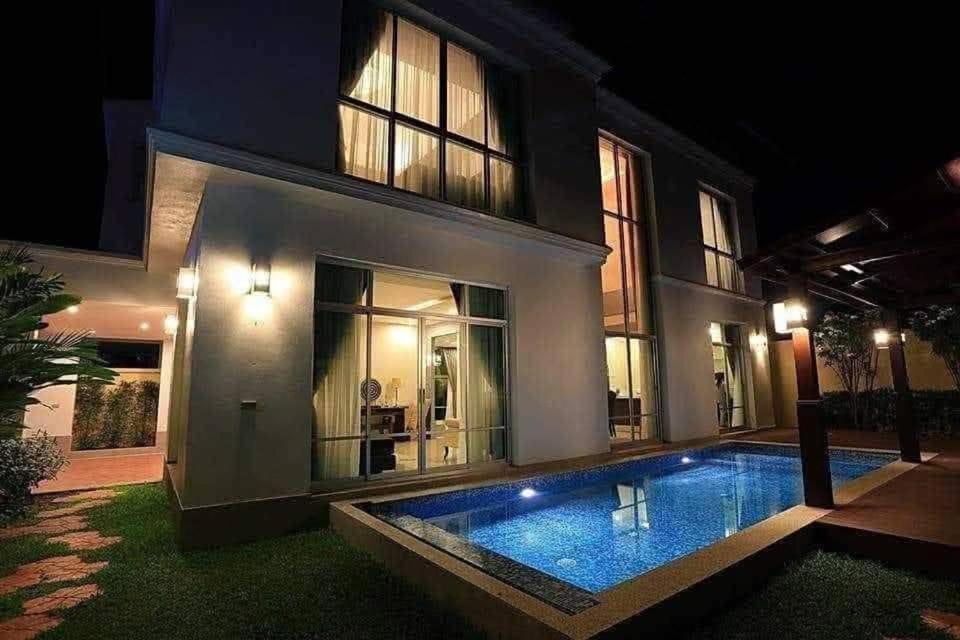 a swimming pool in front of a house at night at BrightFly Pool Villa in Pattaya Central