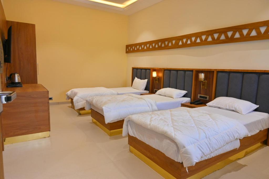 een kamer met 3 bedden met witte lakens bij Ramaya Motel & Resort, Ujjain in Ujjain
