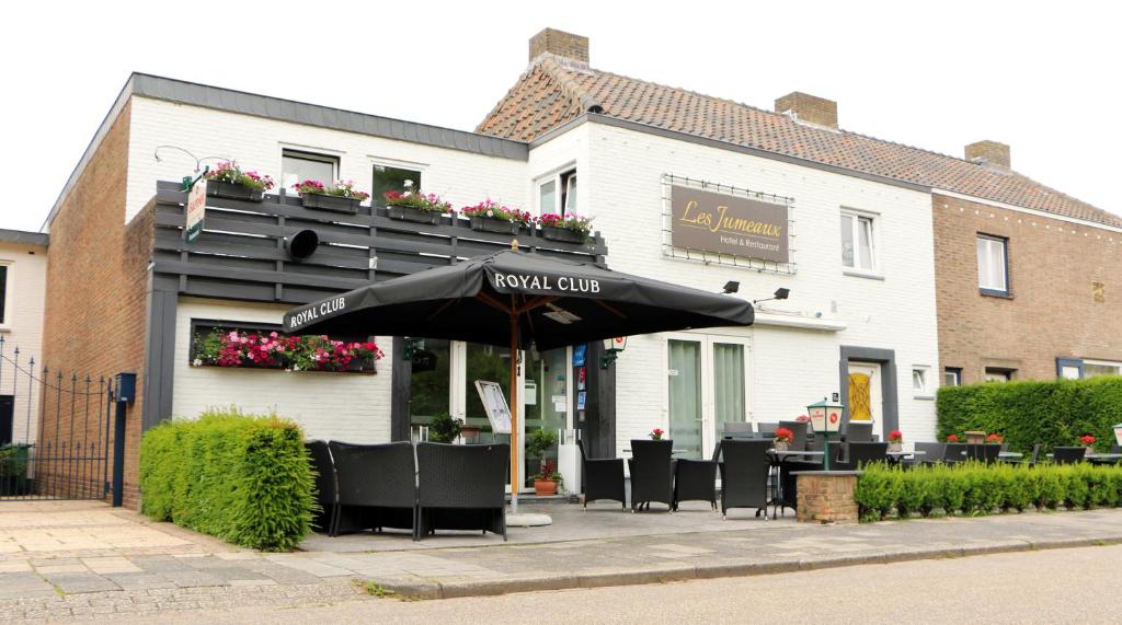 a restaurant with an umbrella in front of a building at Hotel Restaurant Les Jumeaux in Gulpen