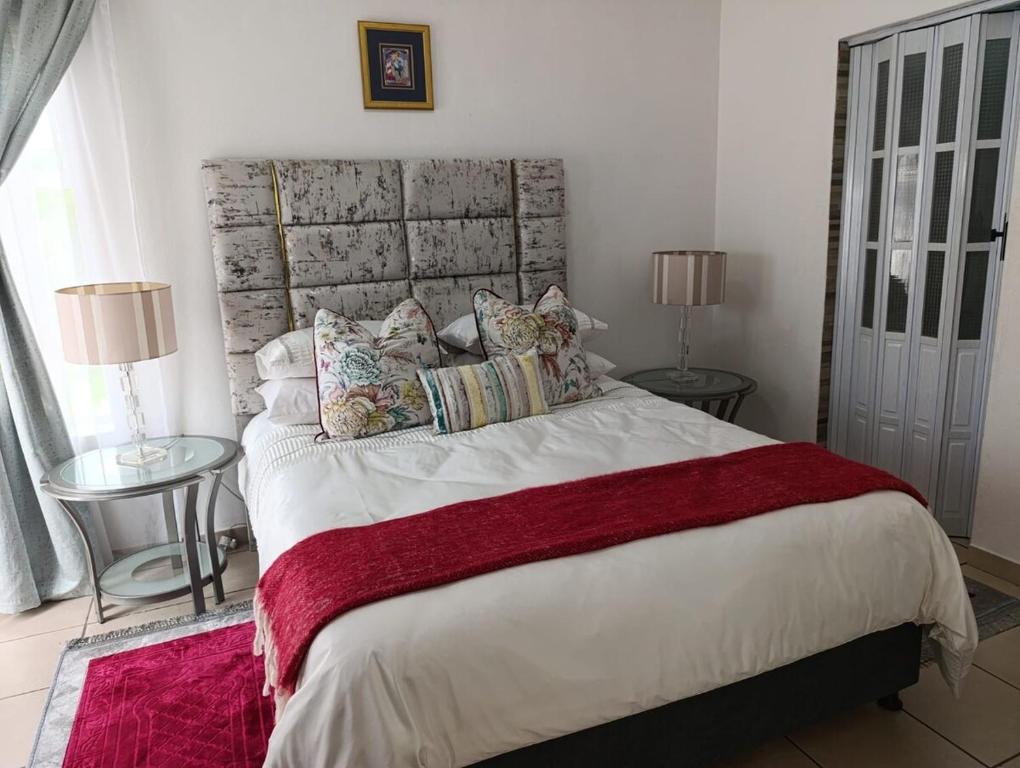 a bedroom with a large bed with two tables and two lamps at Long on Hill in Johannesburg
