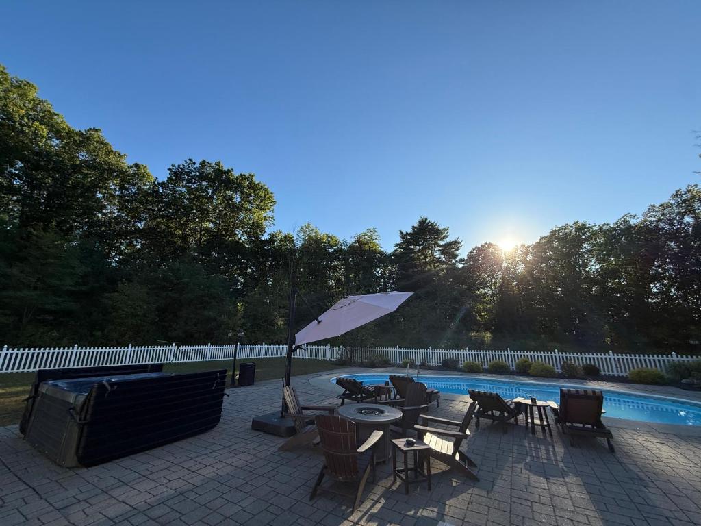 un patio con tavolo, sedie e ombrellone di 9 Bedroom Saratoga Home With In-Ground Heated Pool, HotTub, Firepit, Gourmet Kitchen, Private Office Space On 10 Acres a Saratoga Springs