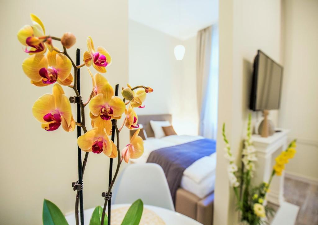 un jarrón lleno de orquídeas amarillas en una habitación en Eden Center Home en Győr