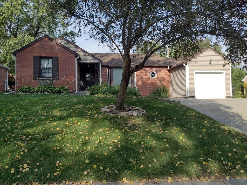 a house with a tree in the front yard at Cozy Brickhouse Indiana Village in Lincoln