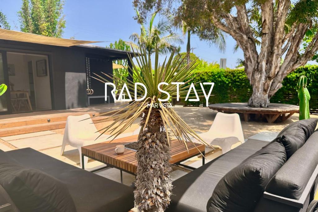 a patio with a couch and a table with a red slay sign at Rad Stay Open Concept House in Mar Vista in Los Angeles