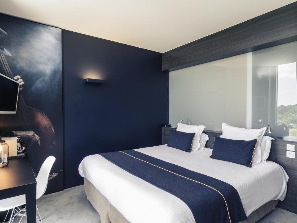 a bedroom with a large bed with blue walls at Hôtel Mercure Nantes Ouest Saint-Herblain Zenith in Saint-Herblain