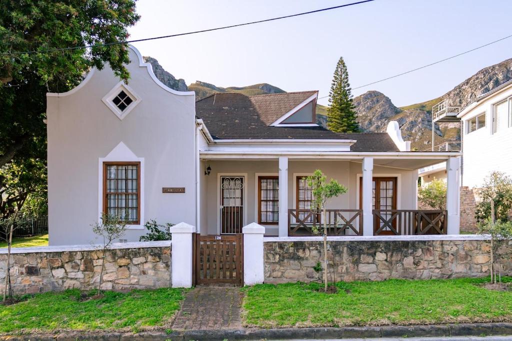 a white house with a stone wall at Mountainside Beach House in Hermanus