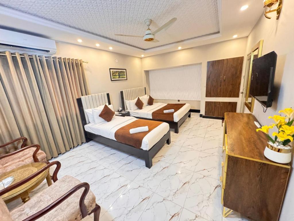 a hotel room with two beds and a tv at Hotel BlueSky Clifton 2 in Dargai