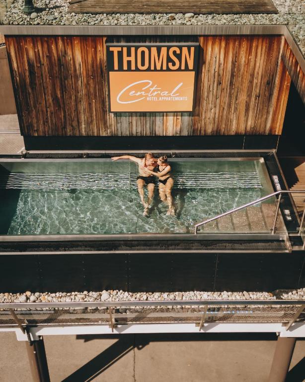 two people sitting in the water in a swimming pool at THOMSN Central Hotel & Appartements in Saalbach-Hinterglemm