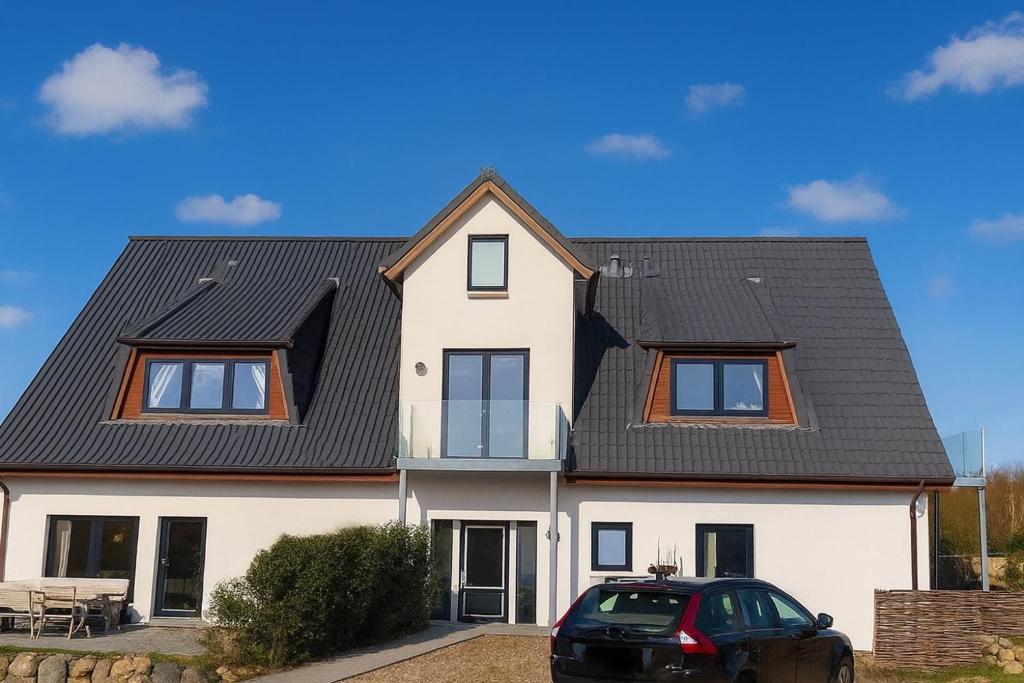 a white house with a black roof at Ferienwohnung Wulf Sylt EG in Wenningstedt