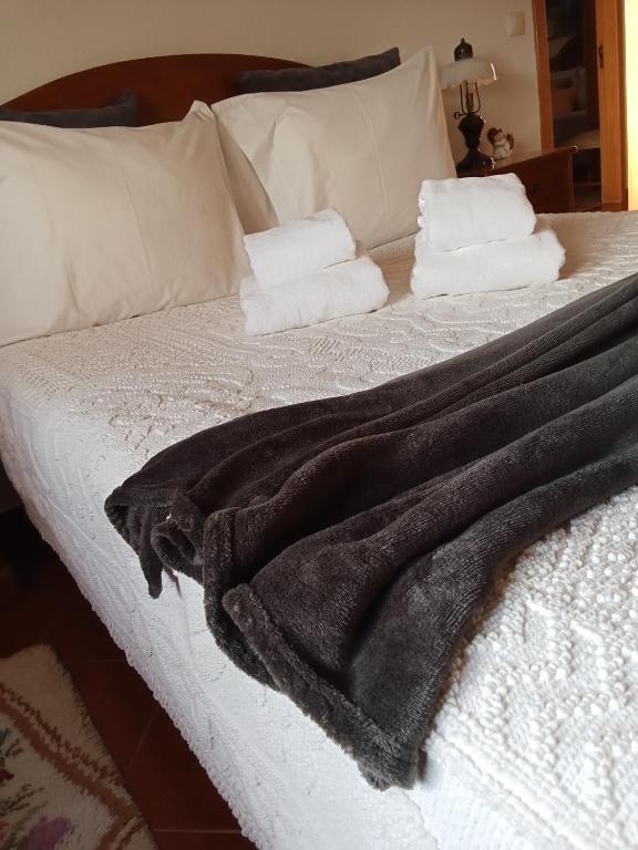 a black blanket on a bed with two towels at Casa do Campo in Seia