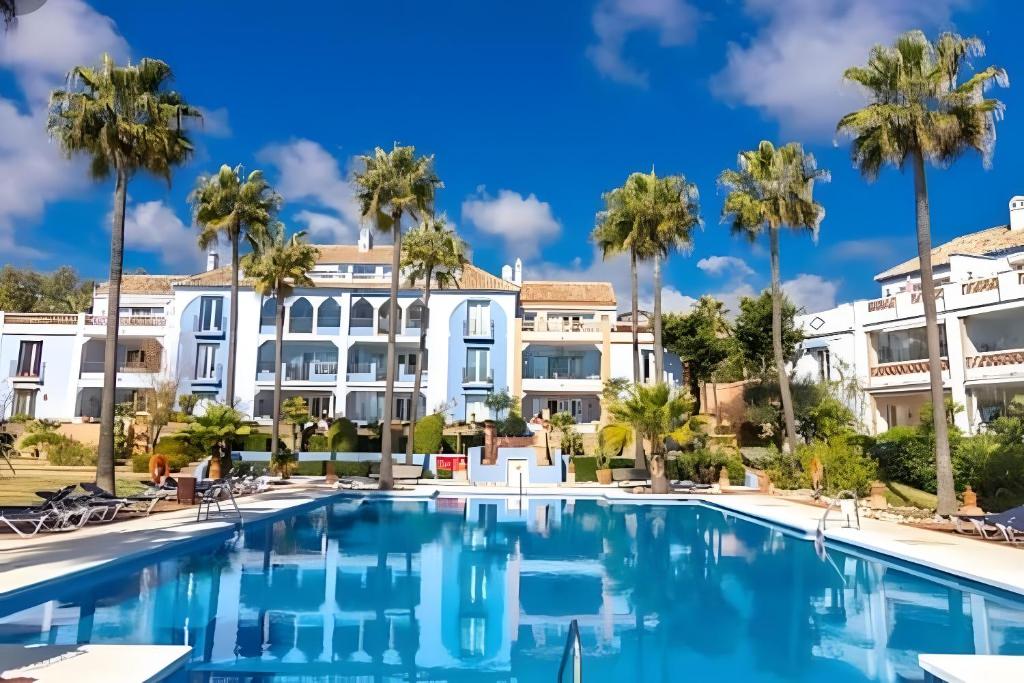 a pool with palm trees in front of a building at La Perla De La Bahía, Espectacular in Bahia de Casares
