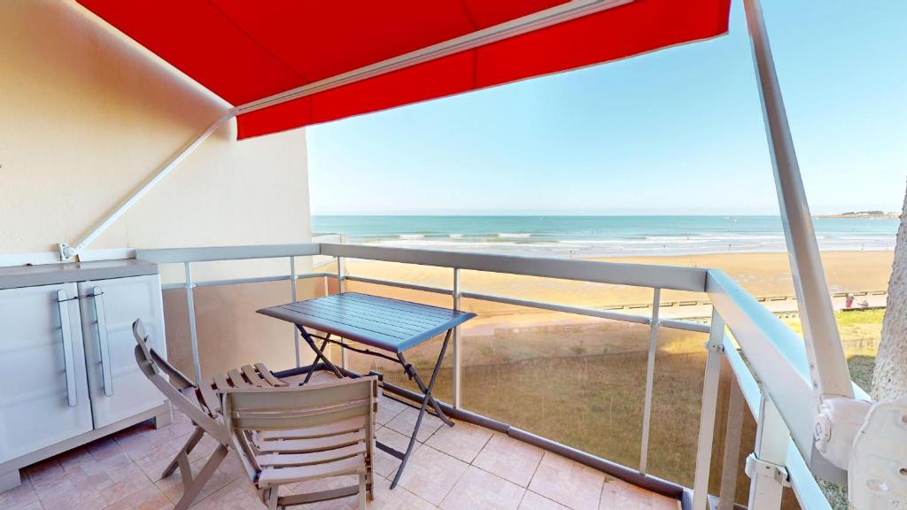 a table and chairs on a balcony with a view of the beach at Panoramic View face Mer in Saint-Gilles-Croix-de-Vie
