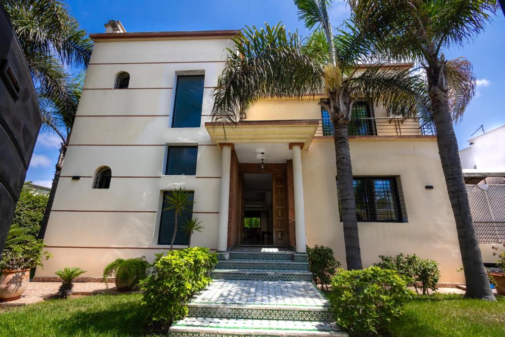 a house with palm trees in front of it at Villa avec piscine 4 chambres proche CFC & tramway Casablanca in Casablanca