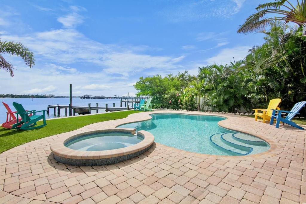 a swimming pool in a patio with chairs and the water at The Bayfront in Bradenton Beach