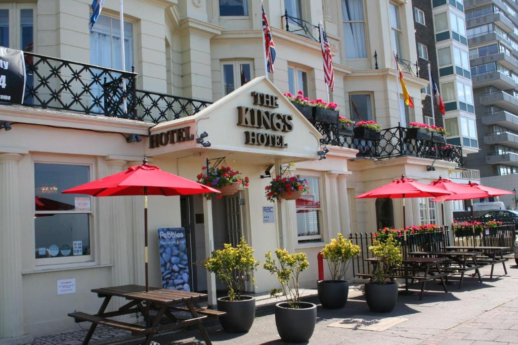 a restaurant with tables and umbrellas on a city street at Kings Hotel in Brighton & Hove