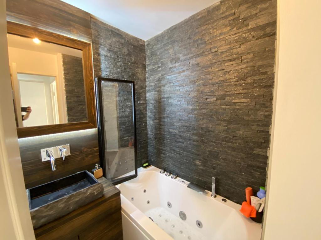 Un baño con bañera, lavabo y espejo. en 2 Pièces d'exception au calme, neuf , 4 personnes, immense terrasse, vue époustouflante , Tout pédestre à 10m du funiculaire, baignoire balnéothérapie, en Isola