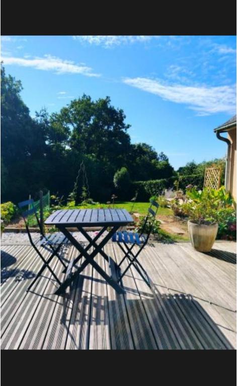 a picnic table and a chair on a wooden deck at Les hortensias in Lannion