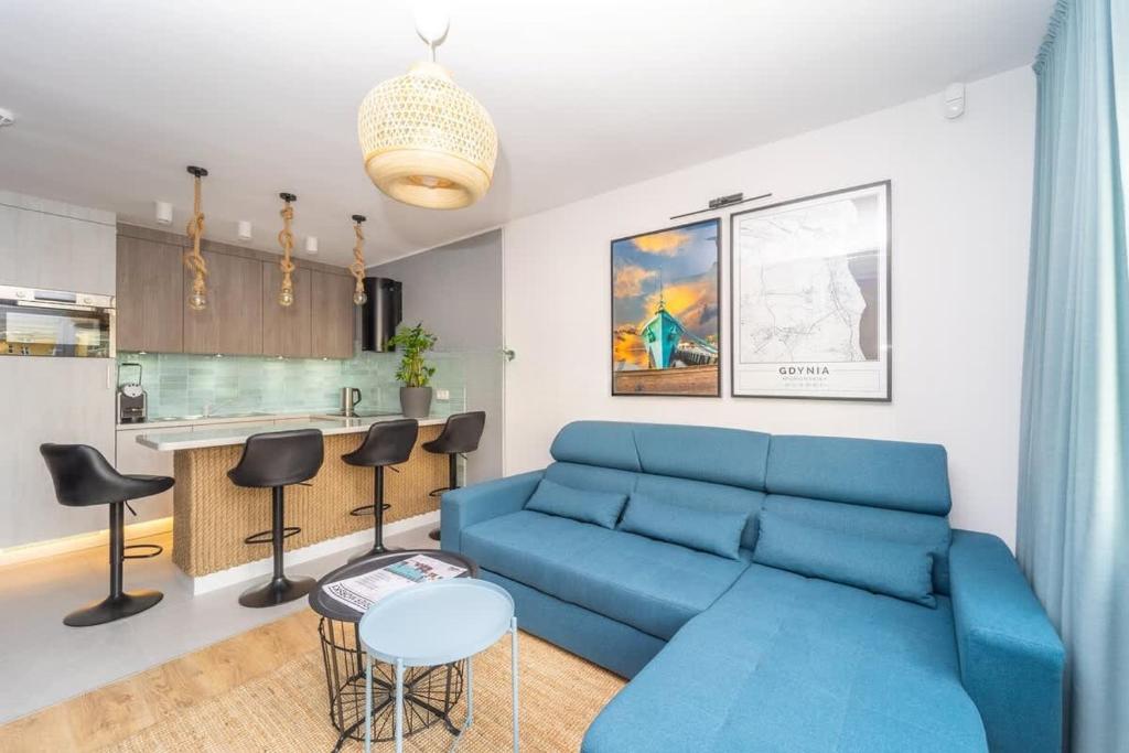 un salon avec un canapé bleu et une cuisine dans l'établissement Bright and Blue 3city Apartment with Balcony in Gdynia by Noclegi Renters, à Gdynia