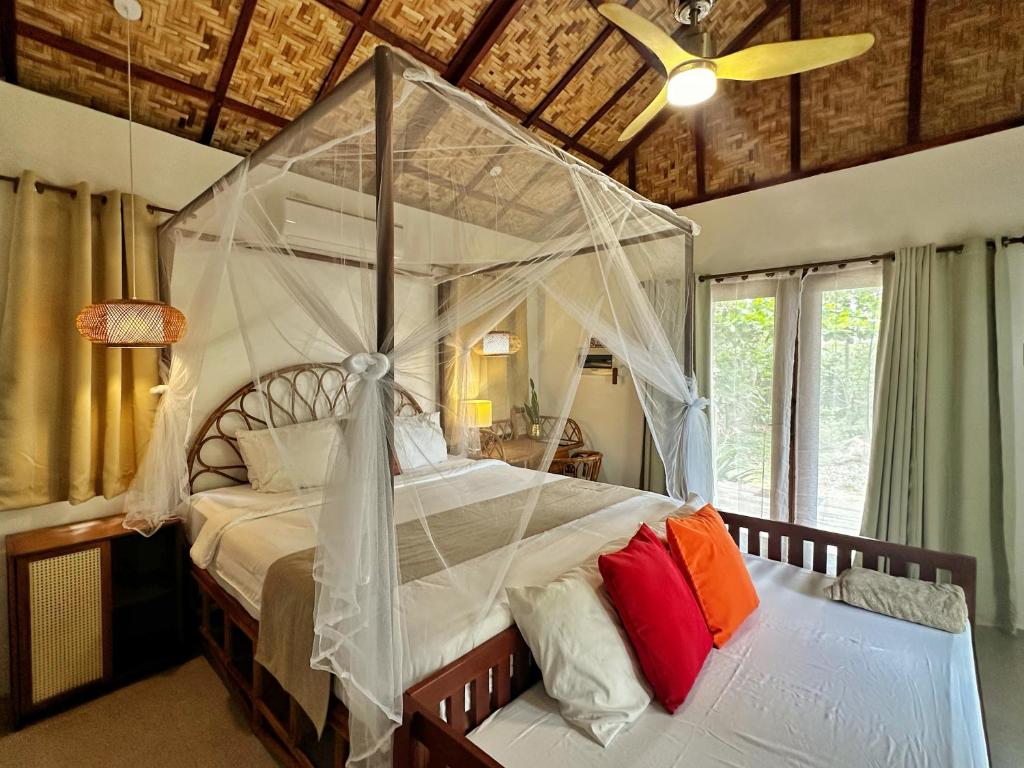 ein Schlafzimmer mit einem großen Bett mit Baldachin in der Unterkunft Uzuri Kubo Huts & Kwartos in Moalboal