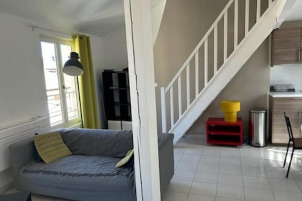 a living room with a blue couch and a staircase at Duplex Mezzanine au calme Place de l'Horloge in Avignon