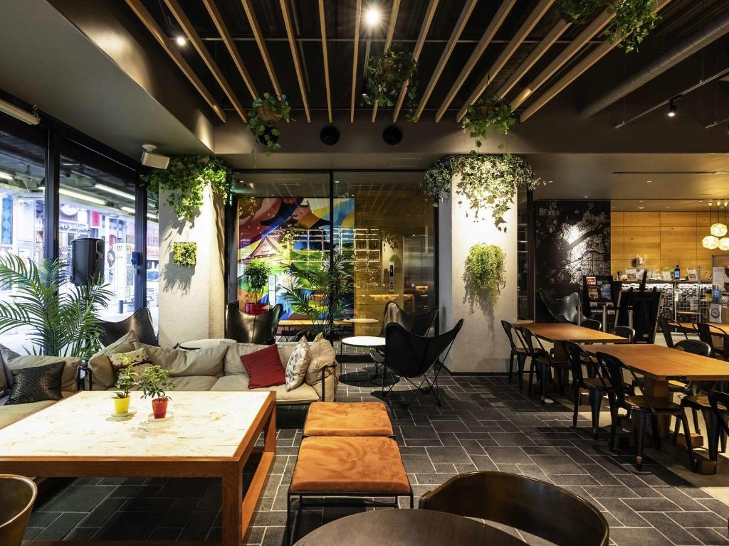 a restaurant with tables and chairs and a couch at ibis Osaka Umeda in Osaka
